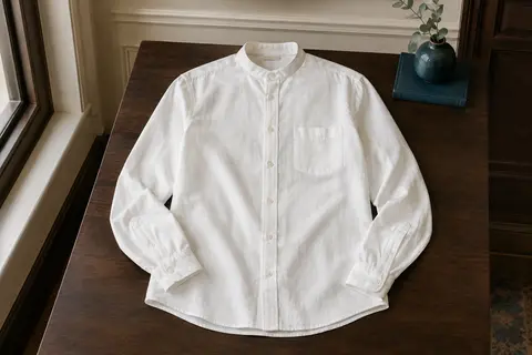 Chemise blanche pour homme à manches longues, avec col mao, poche poitrine et poignets boutonnés, présentée à plat.