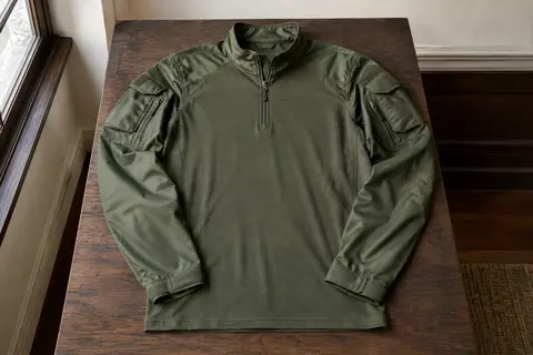 Chemise outdoor verte à manches longues, poches d’épaule et poignets réglables, présentée à plat